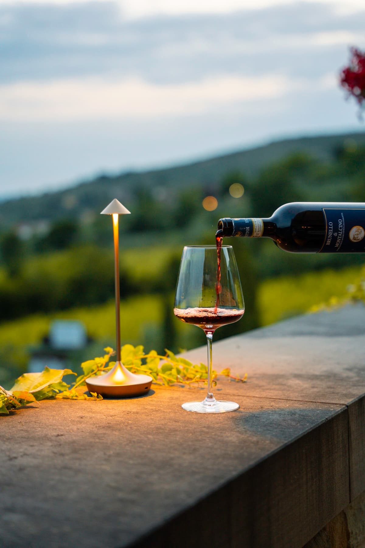 Een glas rode wijn wordt ingeschonken op een terras in Toscane
